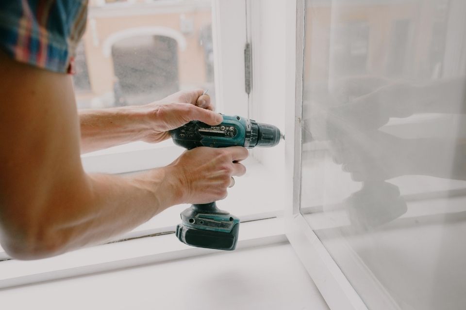 Man using drill to put screws in wall.